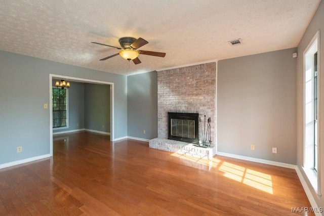 unfurnished living room with visible vents, baseboards, a textured ceiling, and wood finished floors