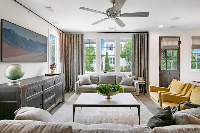 living room with plenty of natural light, light wood-type flooring, ceiling fan, and visible vents