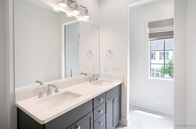 bathroom with a sink, baseboards, and double vanity