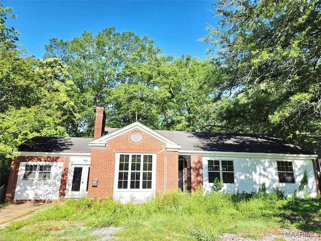 back of house with brick siding and a chimney