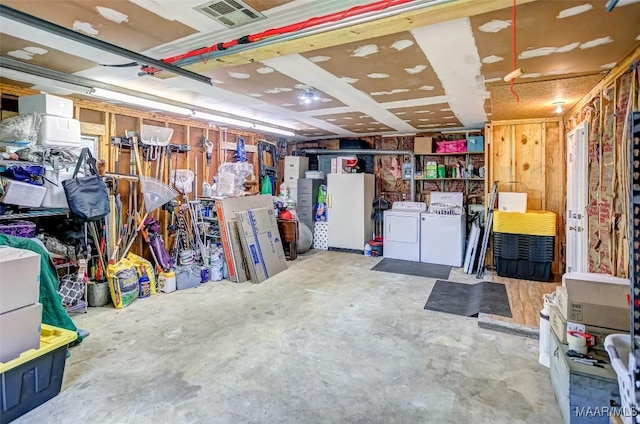 below grade area featuring freestanding refrigerator, visible vents, and washing machine and clothes dryer