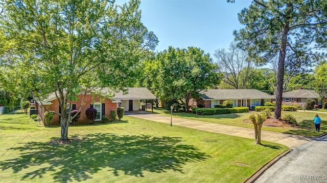 single story home featuring brick siding, a front lawn, and driveway