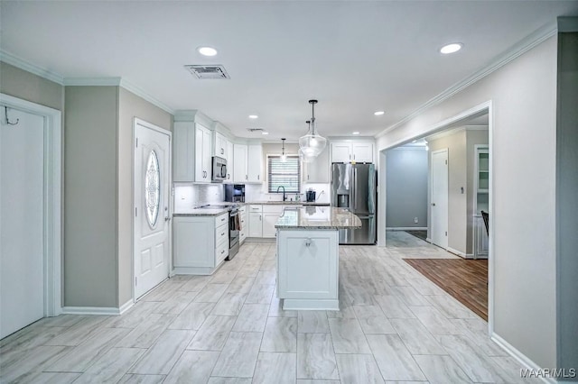 kitchen featuring a sink, appliances with stainless steel finishes, crown molding, and visible vents