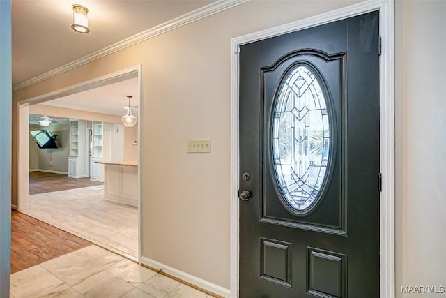 foyer entrance with crown molding, a ceiling fan, and baseboards