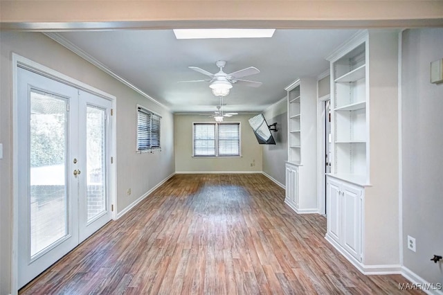 unfurnished living room with a ceiling fan, baseboards, ornamental molding, and wood finished floors