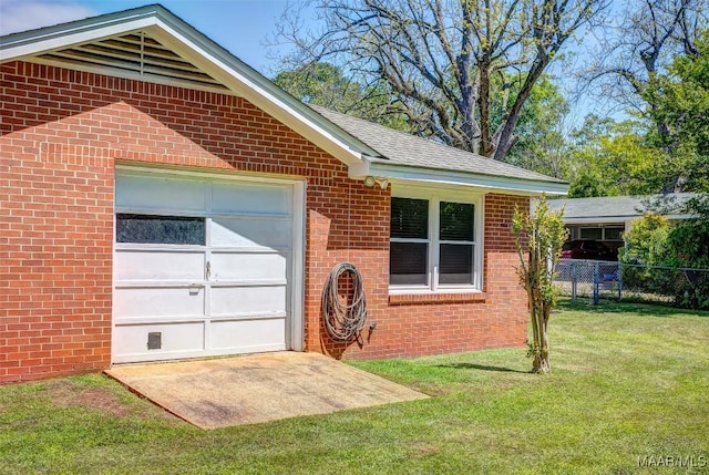 view of side of home featuring a yard, brick siding, an attached garage, and fence
