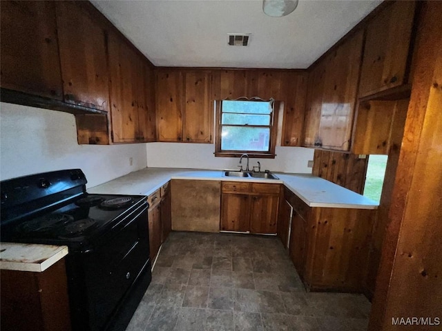kitchen featuring brown cabinets, a sink, light countertops, black electric range oven, and visible vents
