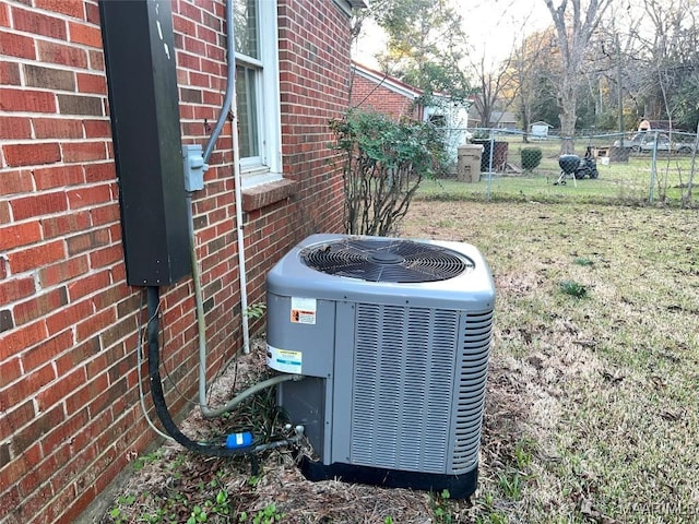 exterior details with brick siding, fence, and cooling unit