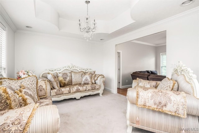 living room featuring an inviting chandelier, baseboards, crown molding, and carpet floors
