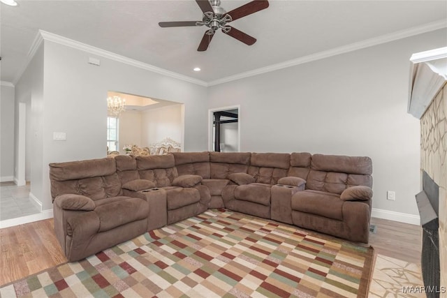 living area featuring light wood-style floors, baseboards, ornamental molding, and ceiling fan with notable chandelier