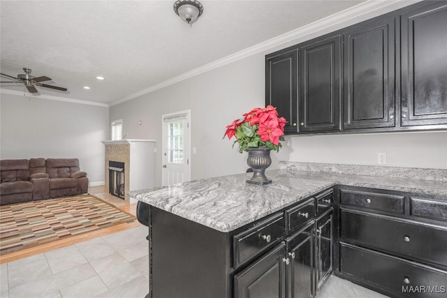 kitchen with crown molding, dark cabinetry, ceiling fan, and open floor plan
