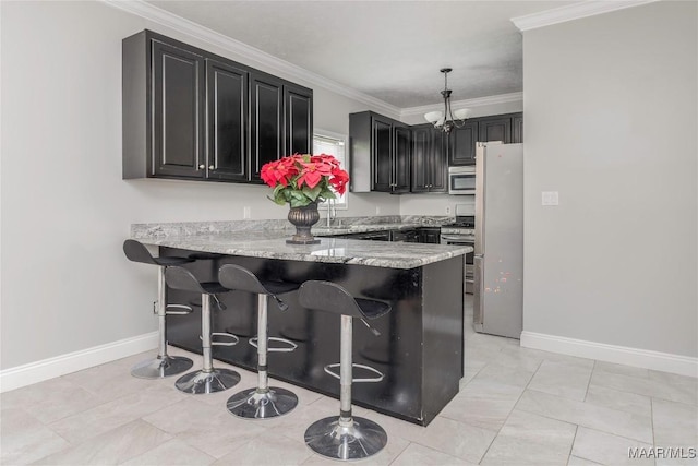 kitchen featuring a notable chandelier, a breakfast bar, dark cabinets, stainless steel appliances, and a peninsula