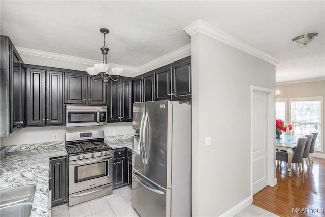 kitchen featuring crown molding, appliances with stainless steel finishes, light stone countertops, an inviting chandelier, and dark cabinetry