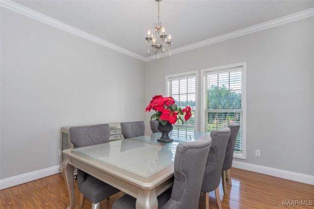dining room with baseboards, an inviting chandelier, ornamental molding, and wood finished floors