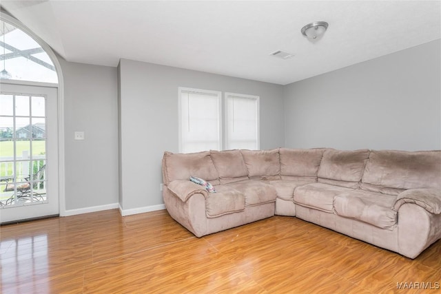 living area featuring baseboards, light wood finished floors, and visible vents