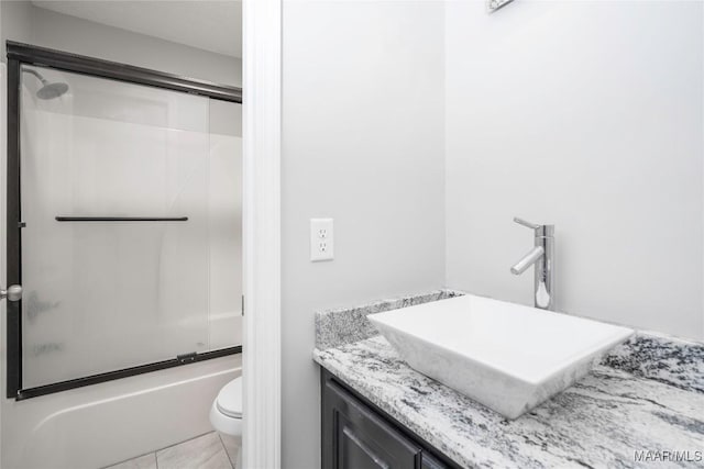 full bath featuring toilet, tile patterned floors, shower / bath combination with glass door, and vanity