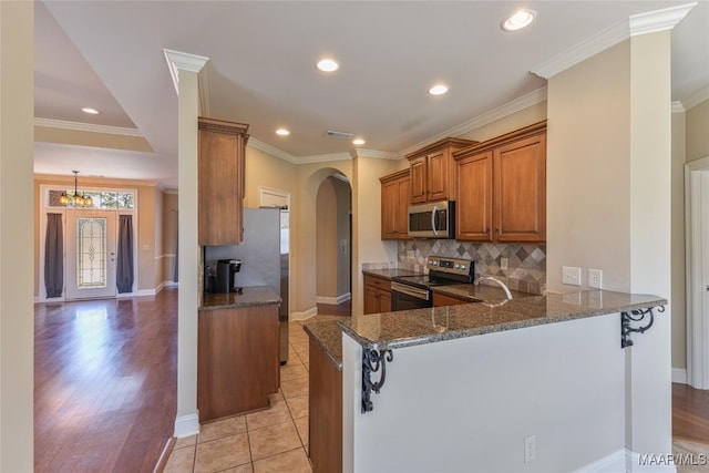 603 Coleman Way, Prattville, AL 36067 - kitchen with brown cabinetry, dark stone counters, recessed lighting, arched walkways, and appliances with stainless steel finishes