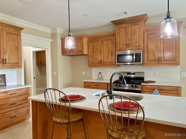 kitchen featuring stainless steel appliances, brown cabinetry, pendant lighting, and a sink