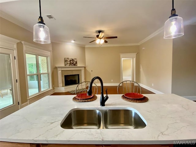 kitchen with a fireplace with raised hearth, decorative light fixtures, visible vents, a sink, and open floor plan