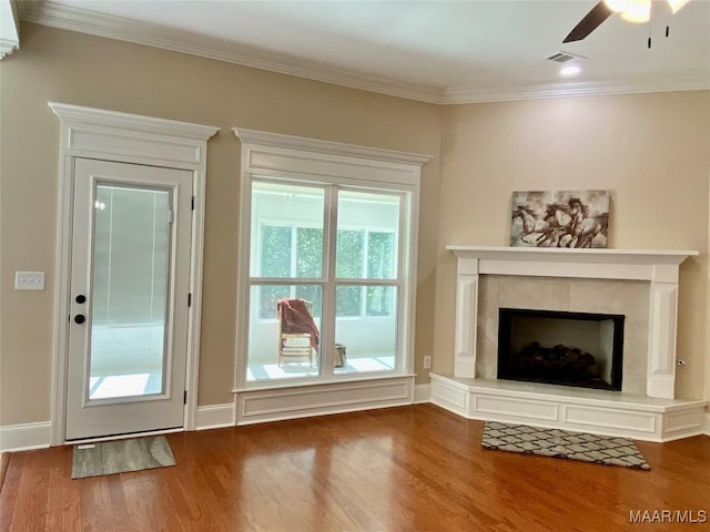 unfurnished living room with a high end fireplace, wood finished floors, ornamental molding, visible vents, and a ceiling fan