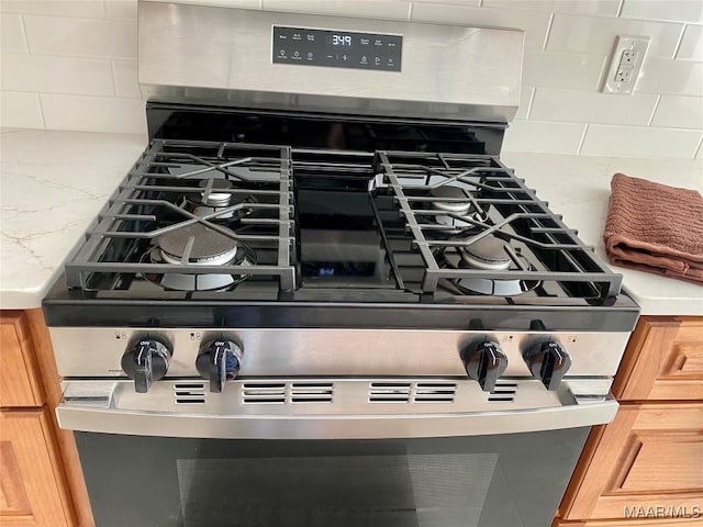 details featuring stainless steel gas range oven and decorative backsplash