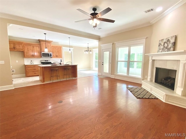 unfurnished living room with a fireplace with raised hearth, visible vents, baseboards, and light wood-style flooring