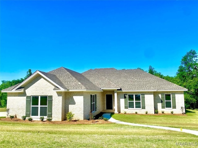 ranch-style home featuring brick siding, roof with shingles, and a front yard