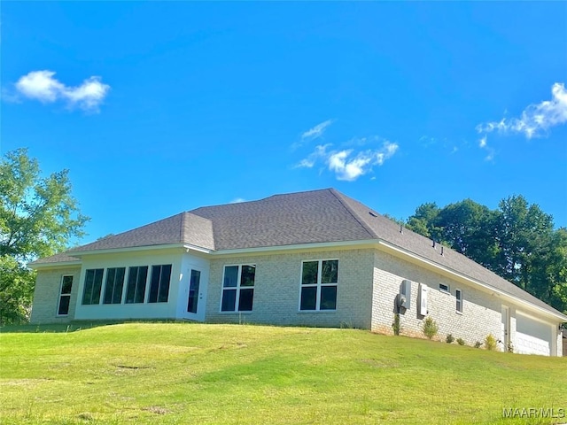 back of house with a yard, brick siding, and a garage