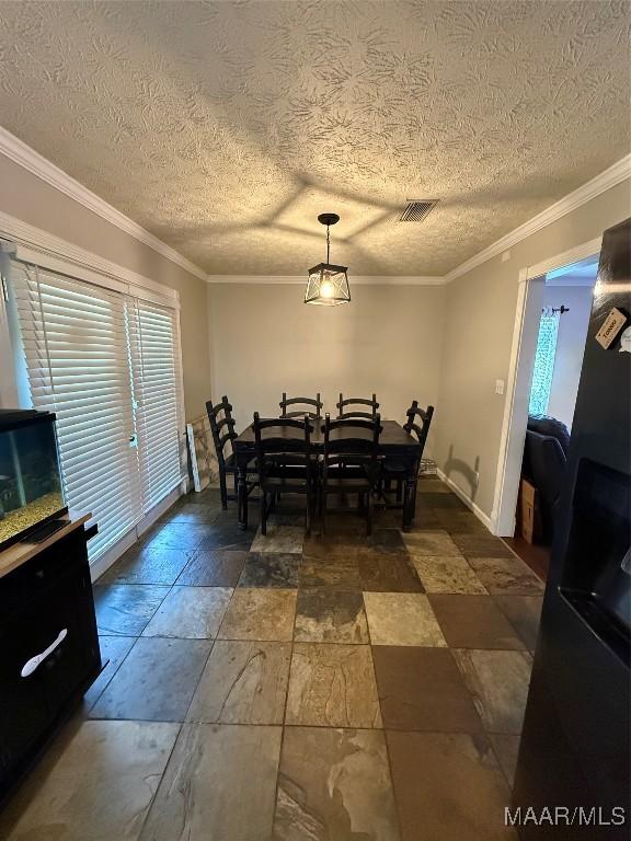 dining room featuring crown molding, a textured ceiling, visible vents, and stone tile floors