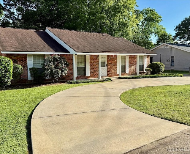single story home featuring curved driveway, brick siding, and a front yard