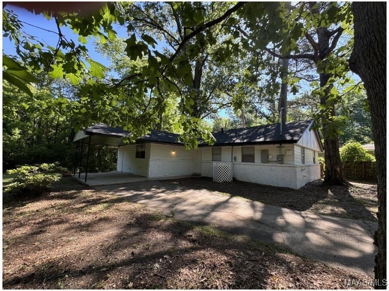 view of front facade with brick siding, dirt driveway, and a carport