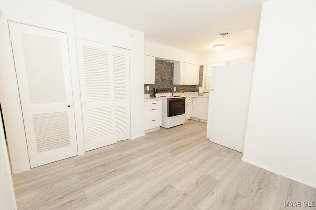 1701 Sylvan Dr, Montgomery, AL 36106 - kitchen with white appliances, light wood-style floors, light countertops, white cabinetry, and backsplash