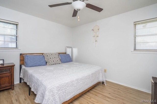 bedroom with multiple windows, light wood-style flooring, and baseboards