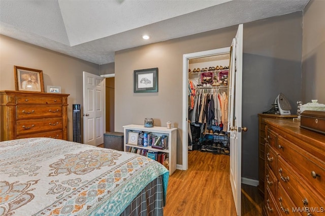 bedroom with a closet, recessed lighting, baseboards, a spacious closet, and light wood-style floors