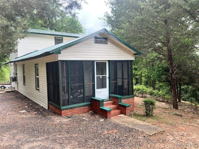 rear view of house featuring metal roof, a sunroom, and entry steps
