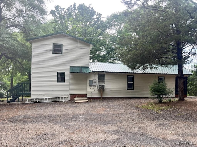 back of house with metal roof and stairway