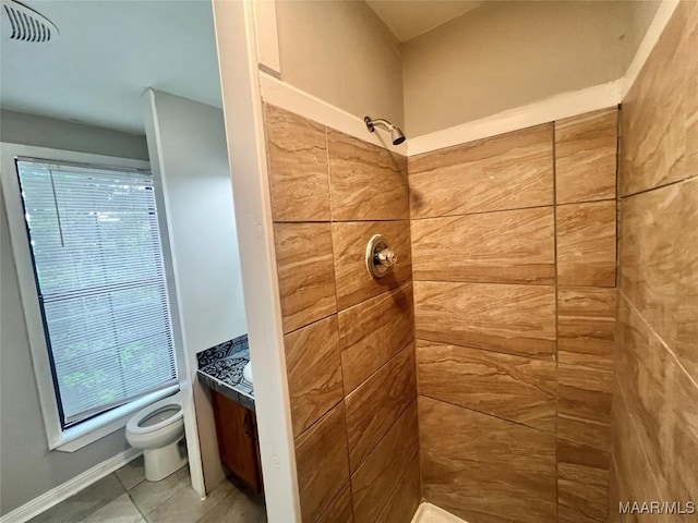 bathroom featuring vanity, toilet, tile patterned flooring, and a tile shower