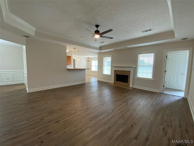 1939 Cedar Ridge Loop, Prattville, AL 36067 - unfurnished living room featuring a tray ceiling, a ceiling fan, dark wood finished floors, ornamental molding, and a textured ceiling