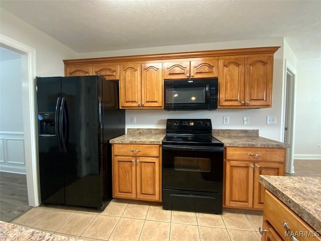 1939 Cedar Ridge Loop, Prattville, AL 36067 - kitchen with black appliances, brown cabinets, light tile patterned floors, dark countertops, and a wainscoted wall