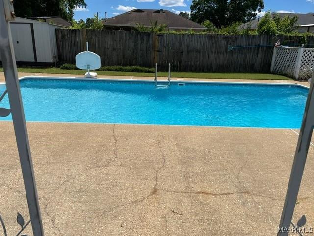 view of swimming pool with a fenced backyard, an outbuilding, and a storage shed
