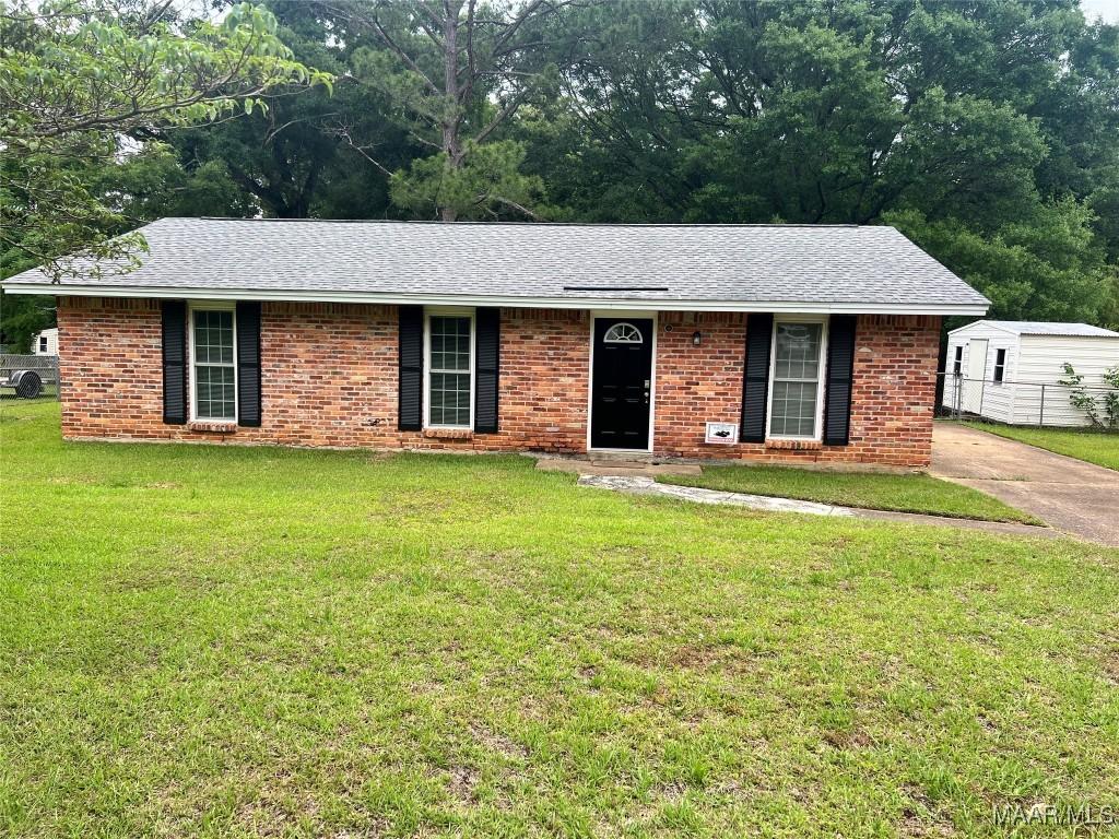 ranch-style home featuring a front lawn, brick siding, and roof with shingles