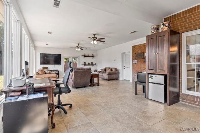office space with visible vents, ceiling fan, and brick wall