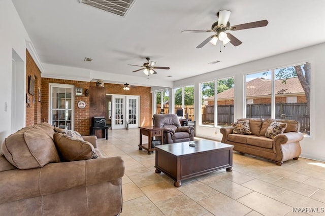 living area featuring visible vents, a ceiling fan, and brick wall