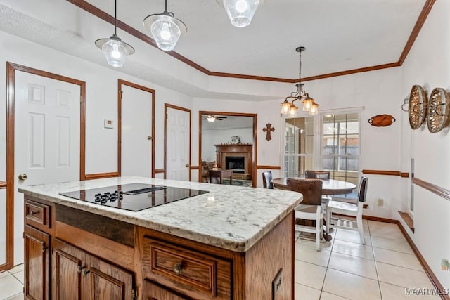kitchen featuring a fireplace, black electric stovetop, pendant lighting, and light tile patterned floors