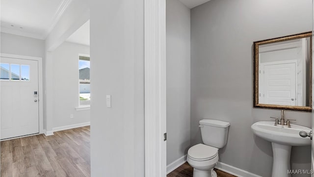 bathroom featuring crown molding, toilet, baseboards, and wood finished floors