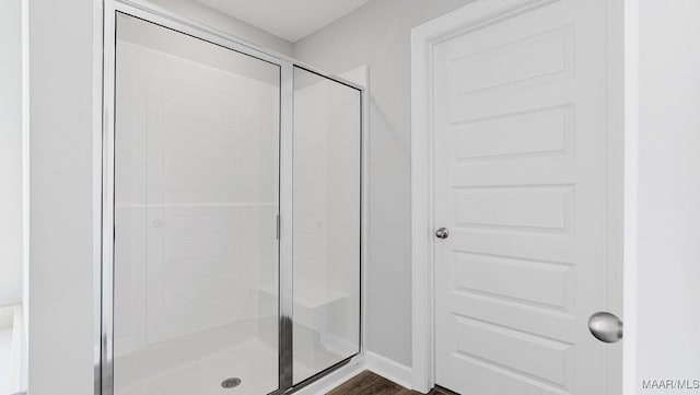 full bathroom featuring a shower stall, baseboards, and wood finished floors
