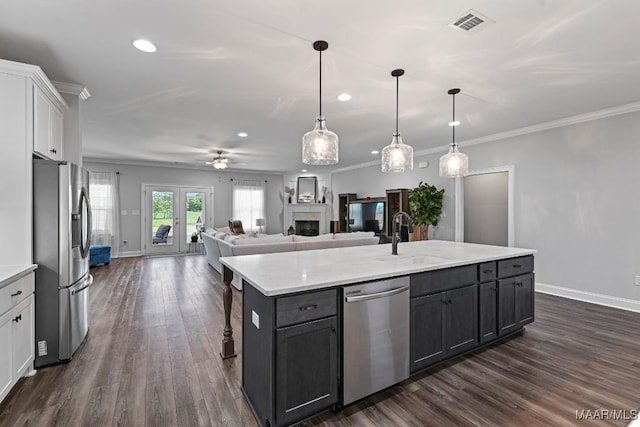 kitchen featuring an island with sink, a sink, white cabinets, appliances with stainless steel finishes, and recessed lighting