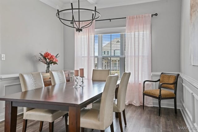 dining room featuring ornamental molding, an inviting chandelier, a decorative wall, a wainscoted wall, and wood finished floors