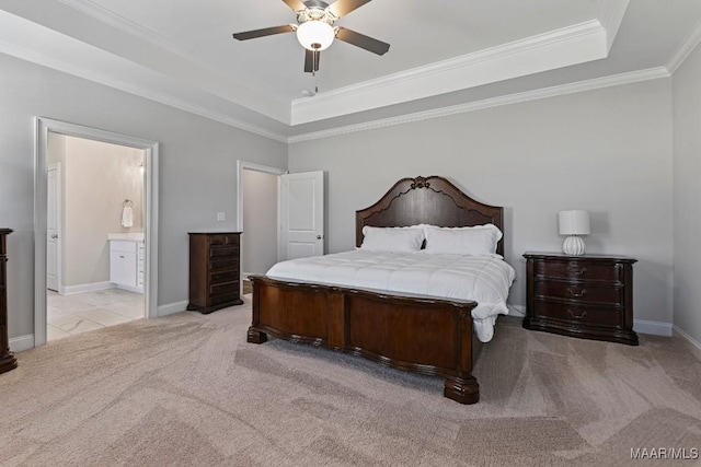bedroom featuring connected bathroom, a tray ceiling, baseboards, light colored carpet, and ornamental molding
