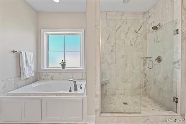 bathroom featuring a stall shower and a bath